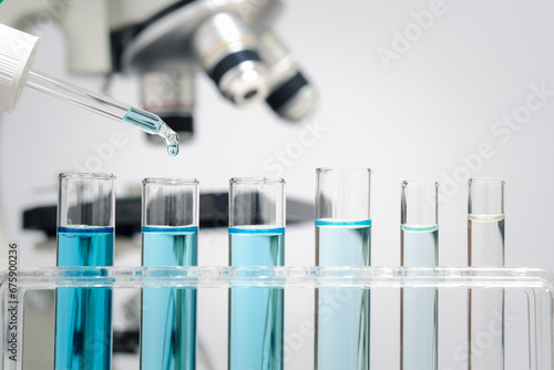 Chemistry laboratory tube glass, science laboratory research and development concept, flask, beaker, and test tubes with dropping blue liquid water sample test, scientific test tubes equipment.