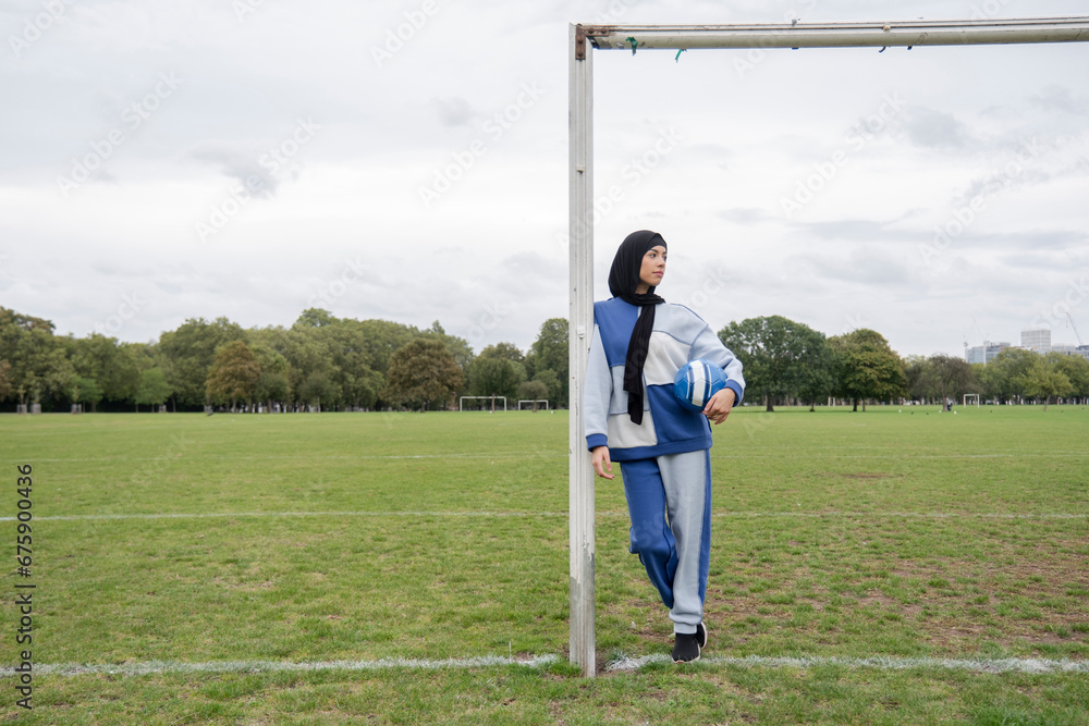 Obraz premium Portrait of woman in hijab standing in soccer field with soccer ball