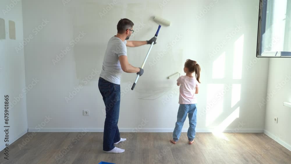 Back view father and little daughter paint wall with rollers at home. Family make renovations in new apartment. Repair concept Back view father and little daughter paint wall with rollers at home. Family make renovations in new apartment. Repair concept