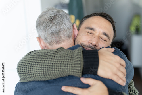 Male couple hugging at home