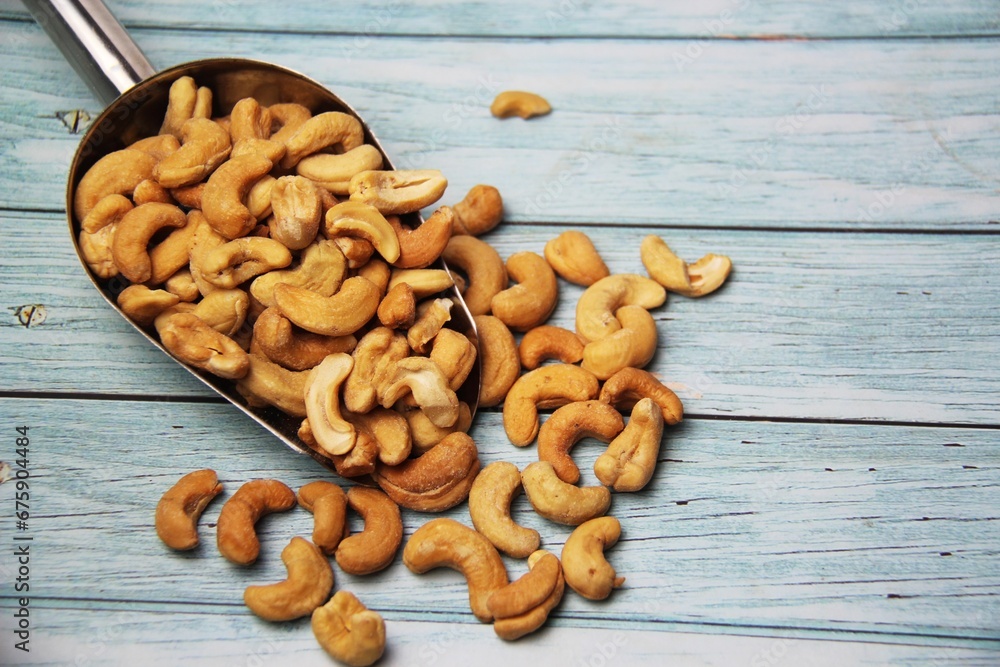 Fototapeta premium Close-up of roasted cashew nuts (Anacardium occidentale) on wooden table, space for text.Top view. Native of Brazil. Rich in magnesium, iron, zinc, selenium, vitamin A, E and antioxidants.