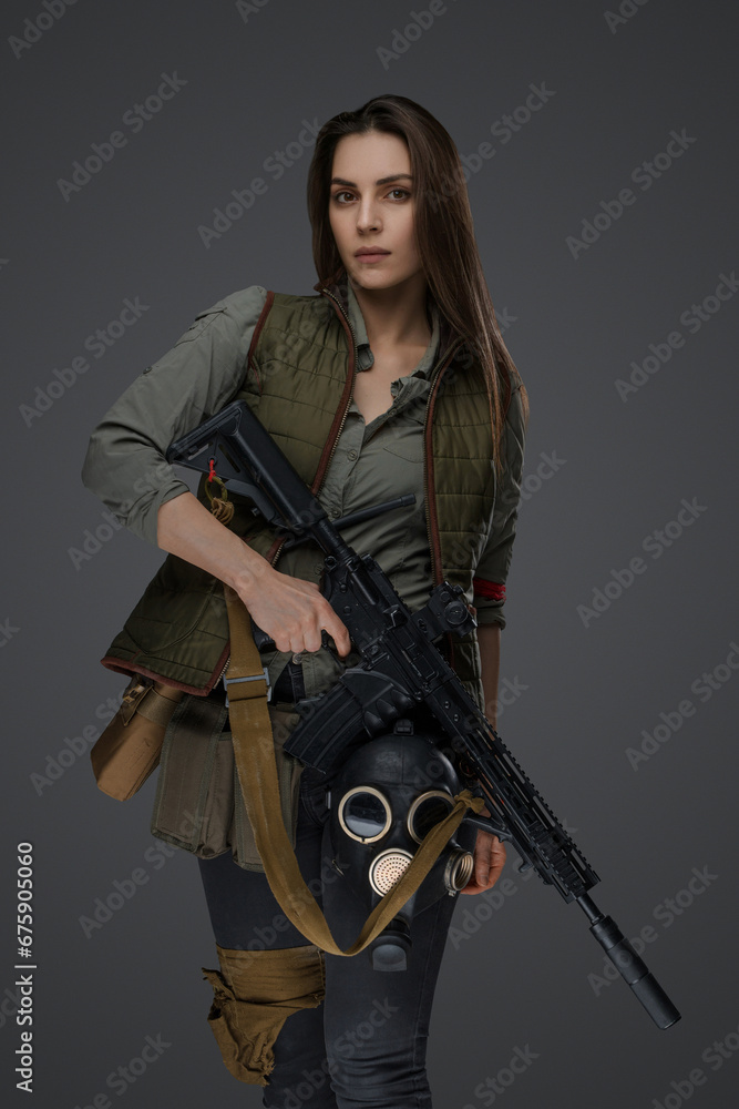 Middle Eastern-looking woman dressed in survivalist clothing posing with a rifle against a gray background, portraying strength and resilience Middle Eastern-looking woman dressed in survivalist clothing posing with a rifle against a gray background, portraying strength and resilience