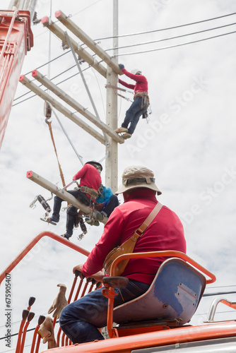 Electricians working on power pole connecting cables 