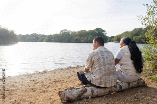 Rear view of couple sitting on lakeshore