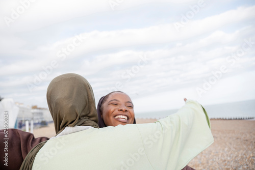 Two Muslim women embracing on beach © Cultura Creative