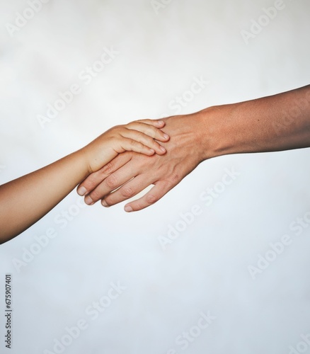 Young child holding their mother's hand against a white background.