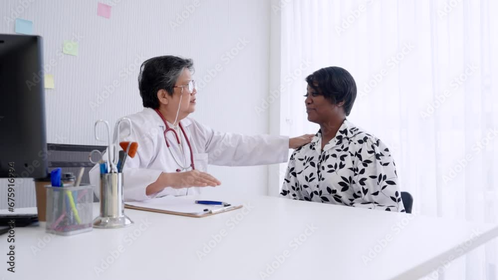 Senior Asian woman doctor, sitting in examination room, with beautiful American female patient, doctor is examining patient's body by pressing hand on chest, and back, check where pain is, how. Senior Asian woman doctor, sitting in examination room, with beautiful American female patient, doctor is examining patient's body by pressing hand on chest, and back, check where pain is, how.