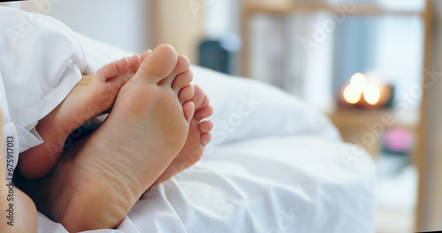 Feet, love and a couple sleeping in bed together for romance or bonding in their home in the morning. Relax, dating or playful with a man and woman barefoot in the bedroom of their apartment closeup