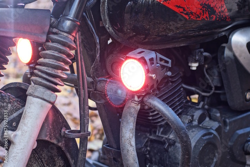 Fototapeta Naklejka Na Ścianę i Meble -  one small round red glass headlight turn signal on a black motorcycle on the street