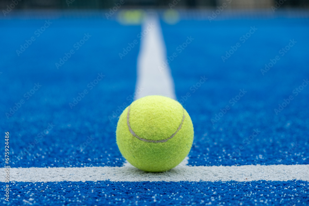 selective focus of a paddle tennis ball on the line of a blue paddle tennis court
