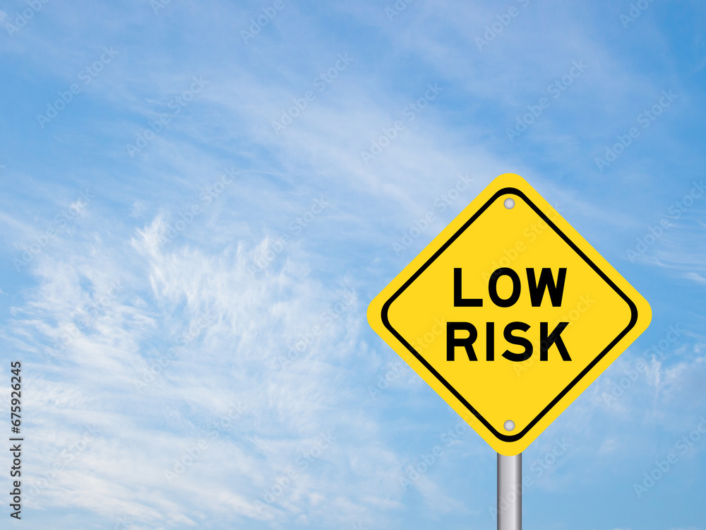Yellow transportation sign with word low risk on blue color sky background Yellow transportation sign with word low risk on blue color sky background