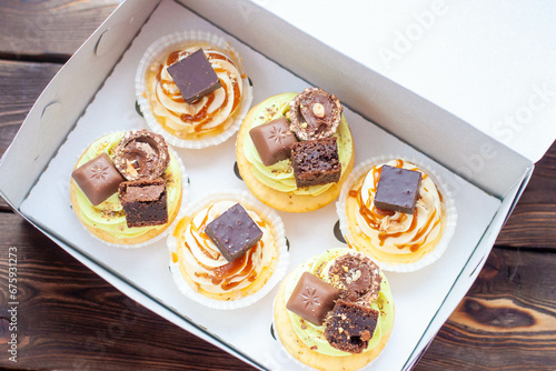 Salted caramel pistachio cupcakes with syrup, pretzels and bites of chocolate in gift box