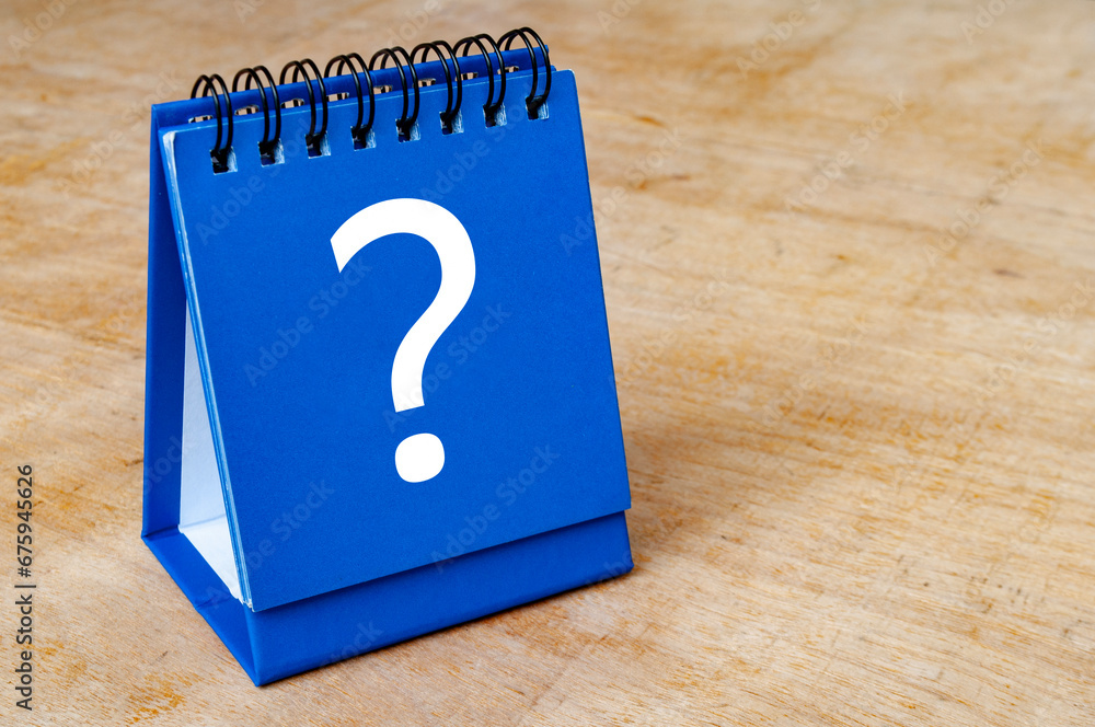 Close up of question mark on blue notepad on wooden background. Question and answer session Close up of question mark on blue notepad on wooden background. Question and answer session