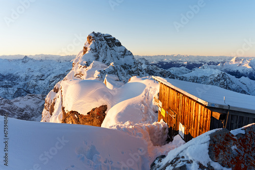 Die eingeschneite und freigeschaufelte Biwakschachtel zum Sonnenuntergang am Watzmann Hocheck in den Berchtesgadener Alpen im Winter mit Blick auf die Watzmann Überschreitung photo