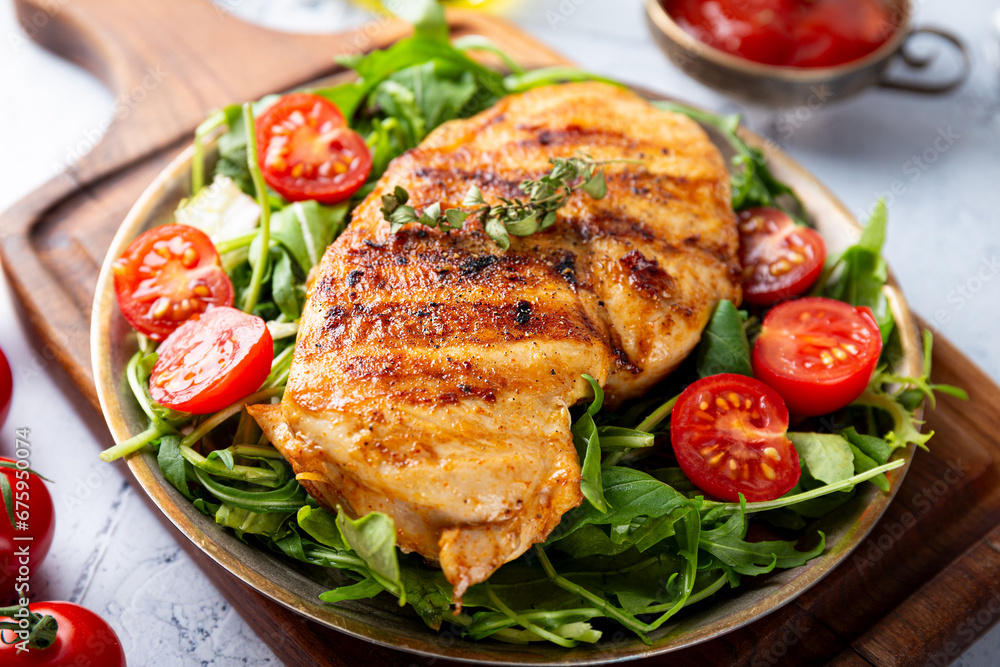 Grilled chicken breast with arugula and tomatoes on a plate Grilled chicken breast with arugula and tomatoes on a plate