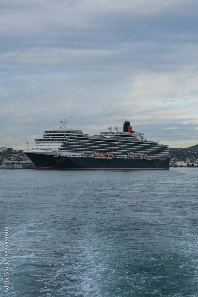 Classic british luxury ocean liner cruiseship cruise ship in port with detail view of steel hull, bow, superstructure and bridge in black, white and red color paint