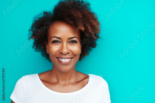 Middle aged woman smiling and wearing a white t-shirt on a turquoise background