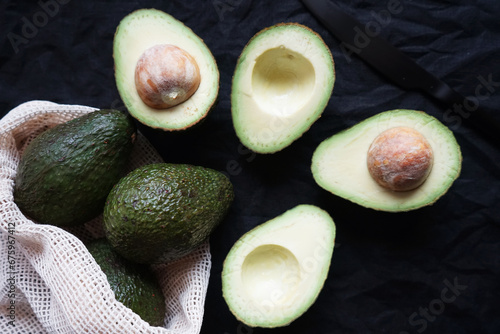 Cut ripe avocado next to other avocados on a dark background