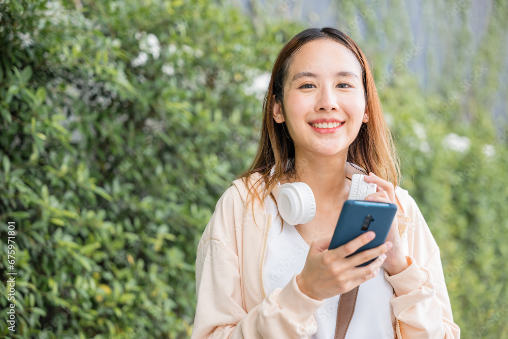 A happy and relaxed young woman is engrossed in her favorite energetic music using wireless headphones while dancing in the urban city garden. Her joyful expression enhances the season vibrancy. A happy and relaxed young woman is engrossed in her favorite energetic music using wireless headphones while dancing in the urban city garden. Her joyful expression enhances the season vibrancy.