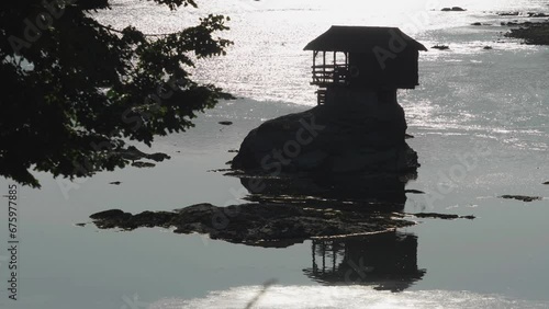 Contre-jour sunset silhouette of little wooden house on top of the rock in the river of Drina in Serbia
