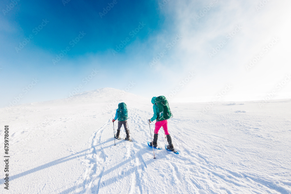 winter activity. Two women walking in snowshoes in the snow, winter hiking, two people in the mountains in winter.