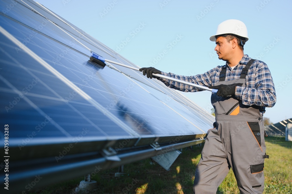 Indian handyman cleaning solar panels form dust and dirt Indian handyman cleaning solar panels form dust and dirt