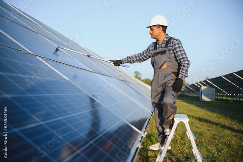 Indian handyman cleaning solar panels form dust and dirt