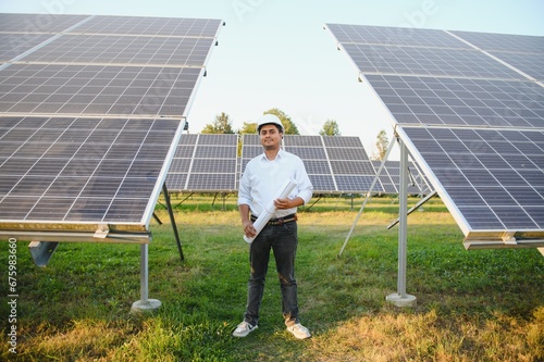 Portrait of Young indian male engineer standing near solar panels  with clear blue sky background  Renewable and clean energy. skill india  copy space