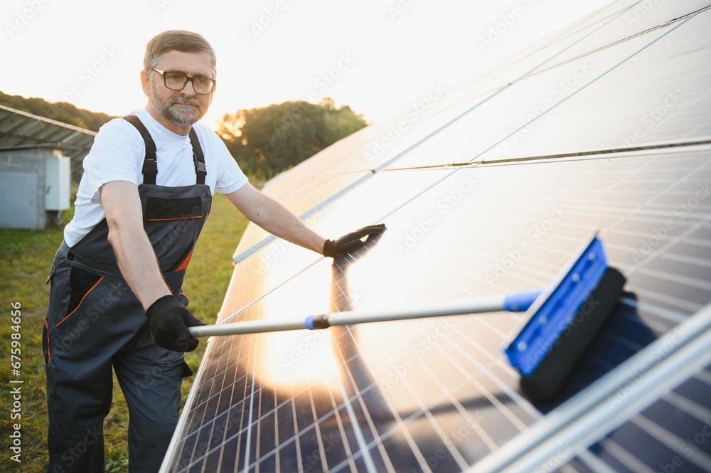 Worker cleaning solar panels after installation outdoors. Worker cleaning solar panels after installation outdoors.