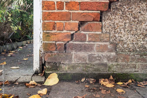 Cracked brick wall in need of repair on boundary of residential premises.