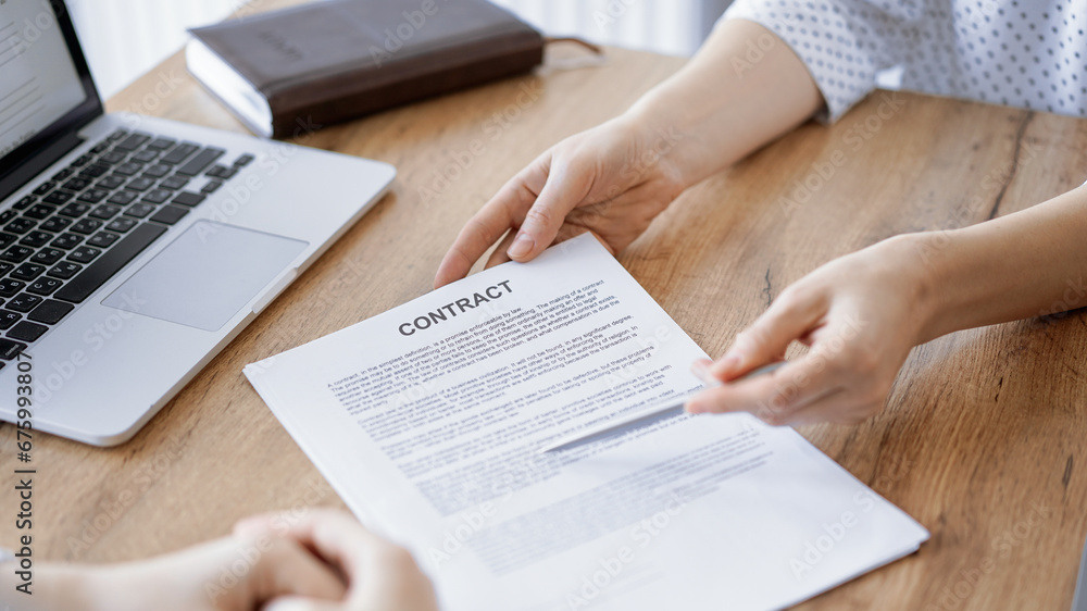 Businesswoman lawyer pointing into contract special points admitting something for colleague or client at the wooden desk in office. Business people teamwork and partnership, meeting concept