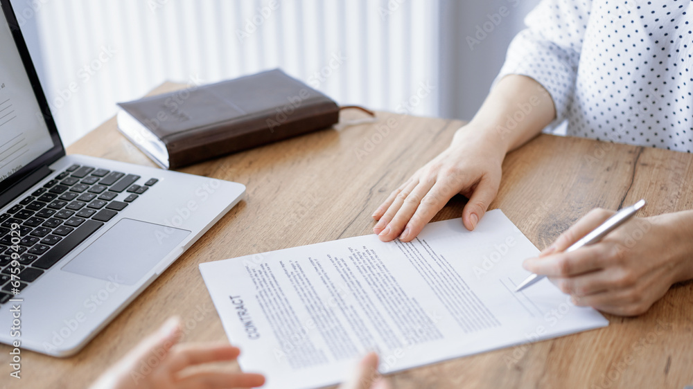 Business people signing contract papers while sitting at the wooden table in office, closeup. Partners or lawyers working together at meeting. Teamwork, partnership, success concept Business people signing contract papers while sitting at the wooden table in office, closeup. Partners or lawyers working together at meeting. Teamwork, partnership, success concept