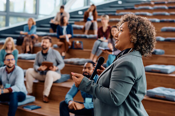 Mature businesswoman giving speech during an education event at convection hall.