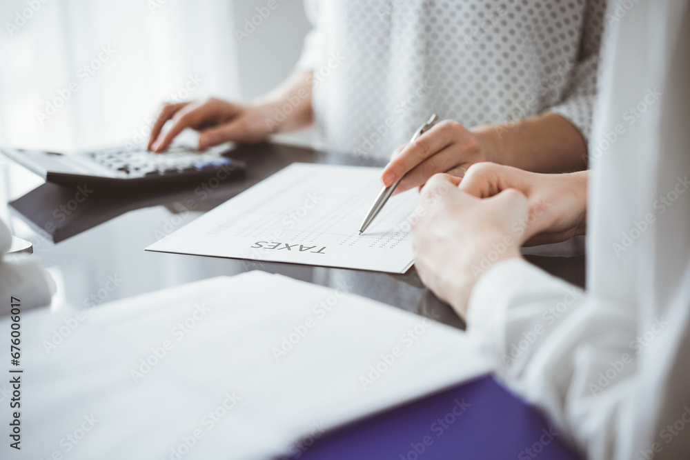 Woman accountant using a calculator and laptop computer while counting taxes for a client. Business audit and finance concepts Woman accountant using a calculator and laptop computer while counting taxes for a client. Business audit and finance concepts