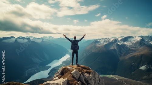 Man standing on top of cliff at sunset.Tourist man hiker on top raised hands and a breathtaking view of mountains,embodying the exhilarating feeling of success and accomplishment 