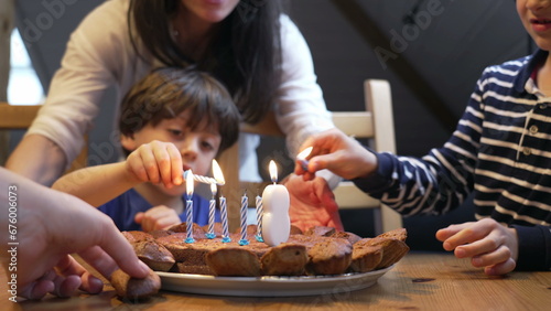 Birthday scene celebration, children lighting candles during 8 year old boy celebration. two brothers in front of cake