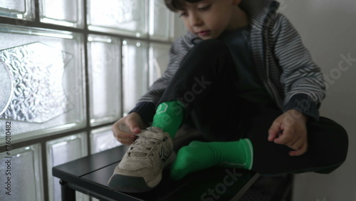 Slika na platnu Child putting shoe on by doorway, kid getting ready to go out