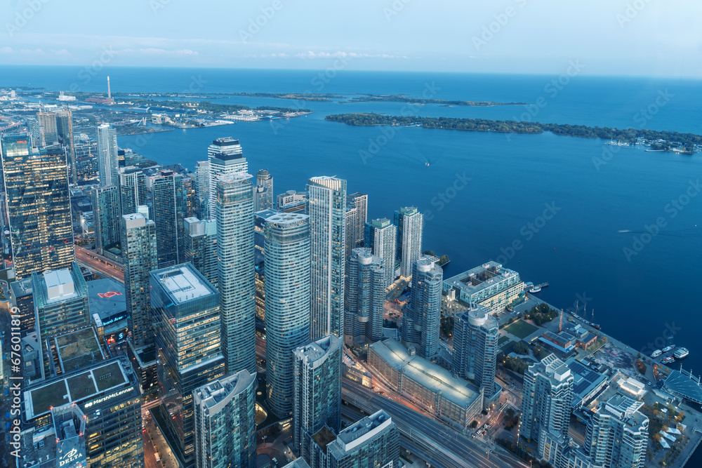 The view of downtown Toronto skyline skyscrapers from the top of CN tower. Lake at dawn, city light bright night long exposure aerial above view
