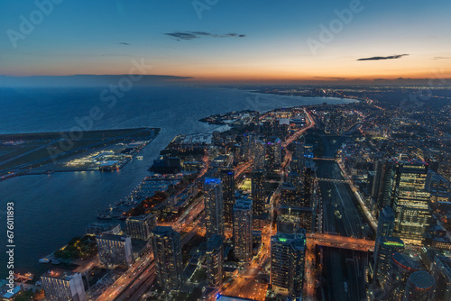 The view of downtown Toronto skyline skyscrapers from the top of CN tower. Lake at dawn, city light bright night long exposure aerial above view