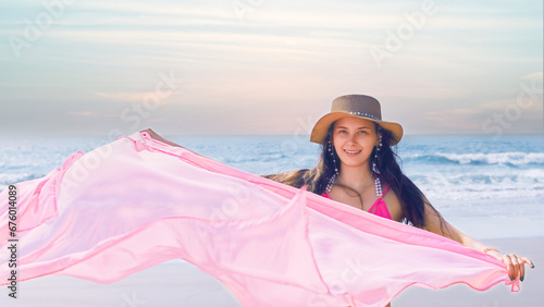 young woman standing against the backdrop of the sea with a pink shawl