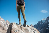 Female walker on top of rocks, blue sky background. Low angle view.