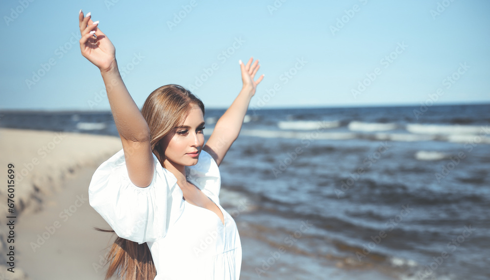 Happy, beautiful woman on the ocean beach standing in a white summer dress, raising hands Happy, beautiful woman on the ocean beach standing in a white summer dress, raising hands