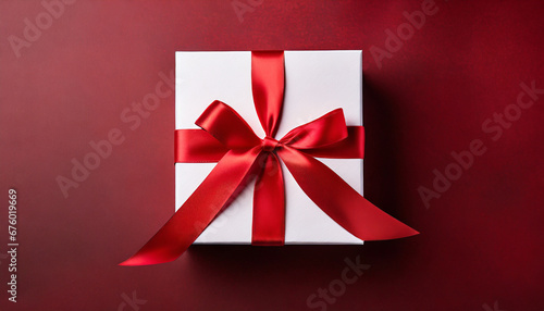 Top view of white present box tied with red ribbon
