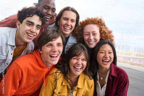 Group portrait of several cheerful young people smiling outdoors. Multiracial joyful friends posing together happy for photo. Community of generation z student having a good time enjoying free time. 