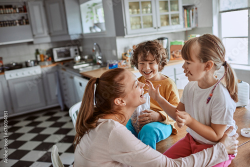 Little girl having fun with mother in kitchen smearing chocolate