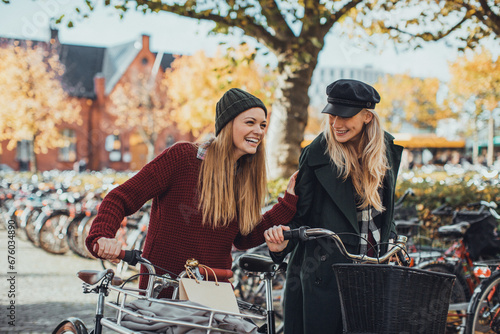 Two stylish young female friends biking in the city © Geber86