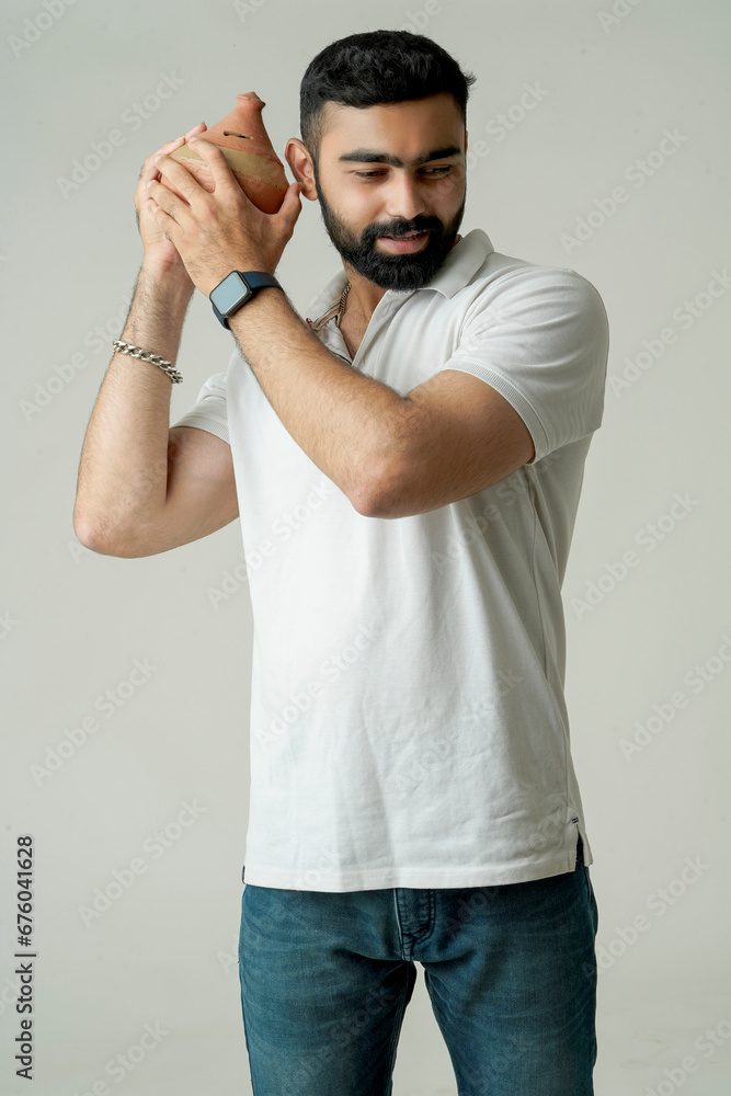 Portrait of Handsome young Indian man holding clay money box or clay piggy bank Portrait of Handsome young Indian man holding clay money box or clay piggy bank