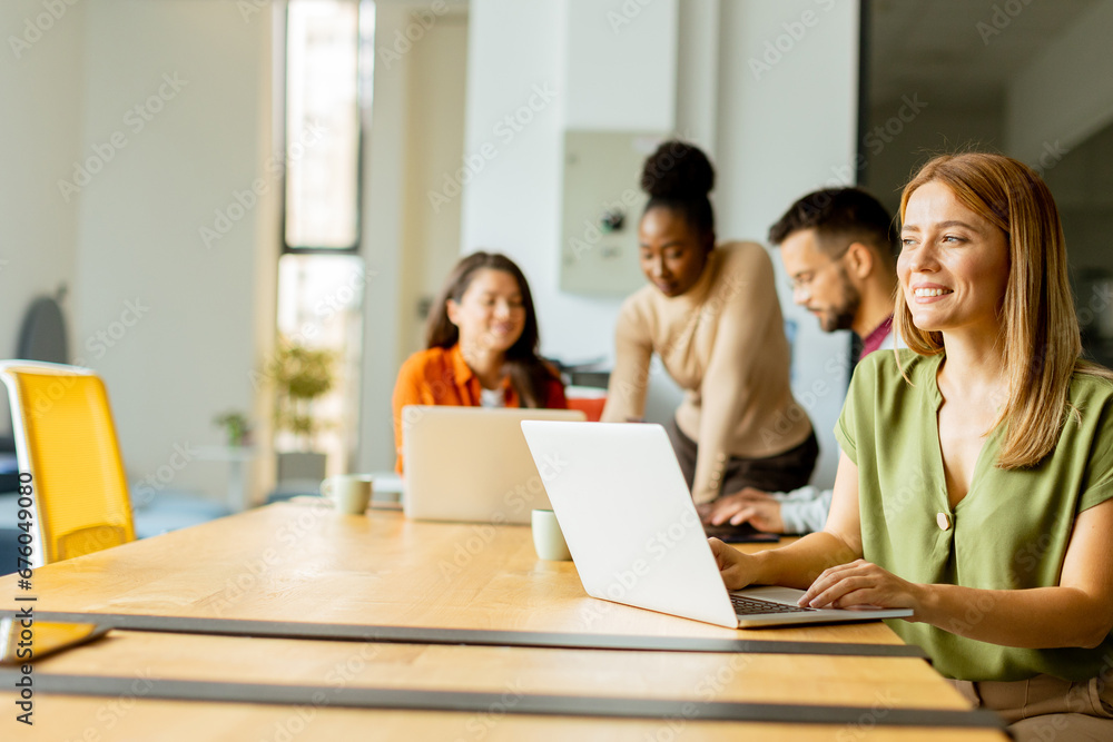 Business woman working on laptop with her young multiethnic startup team working in the modern office Business woman working on laptop with her young multiethnic startup team working in the modern office