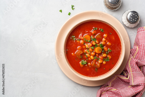 Greek bean soup Fasolada with tomatoes, carrot, celery and onion in bowl on concrete background
