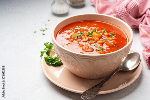 Greek bean soup Fasolada with tomatoes, carrot, celery and onion in bowl on concrete background